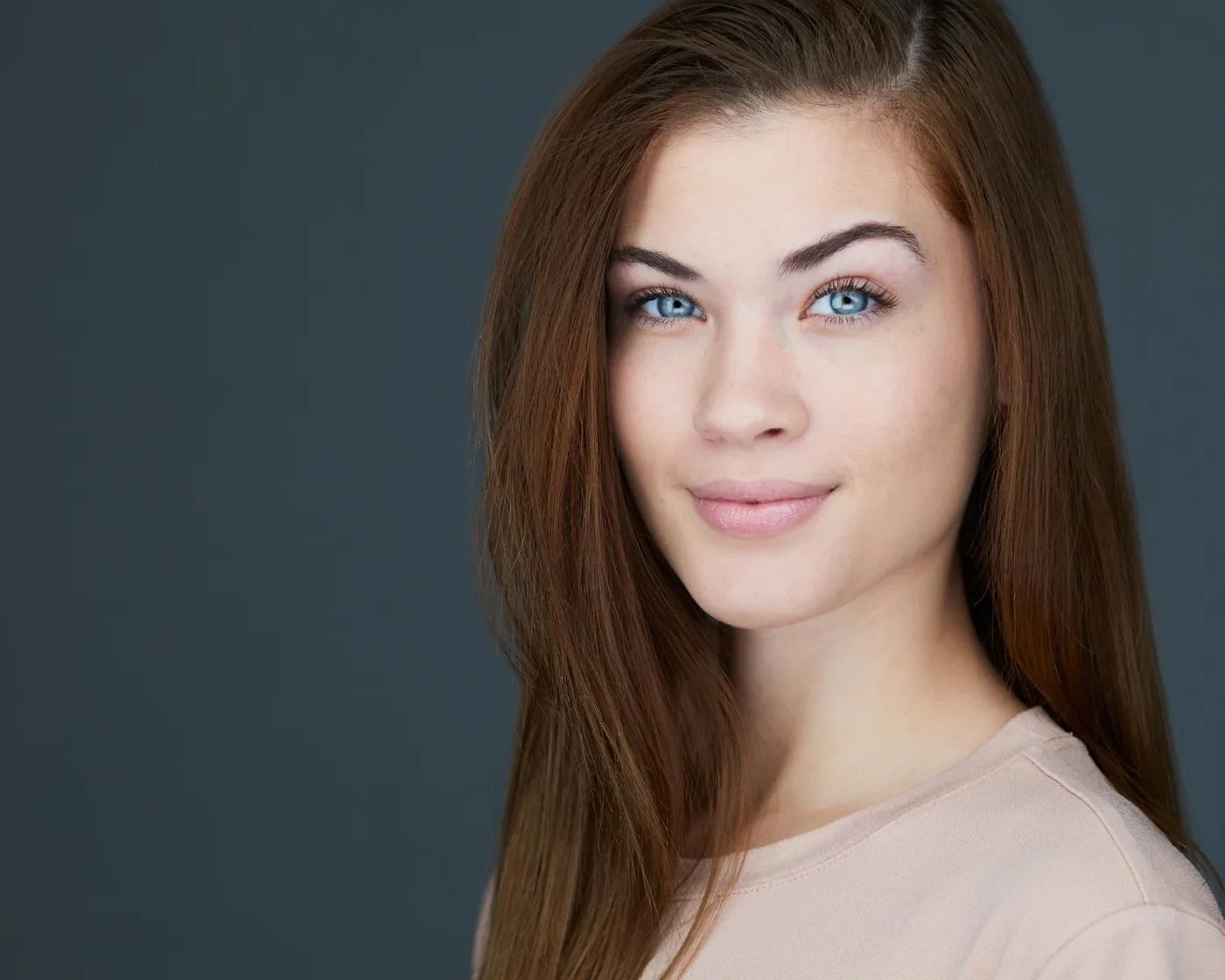 Actor headshot of a young woman with long auburn hair and blue eyes