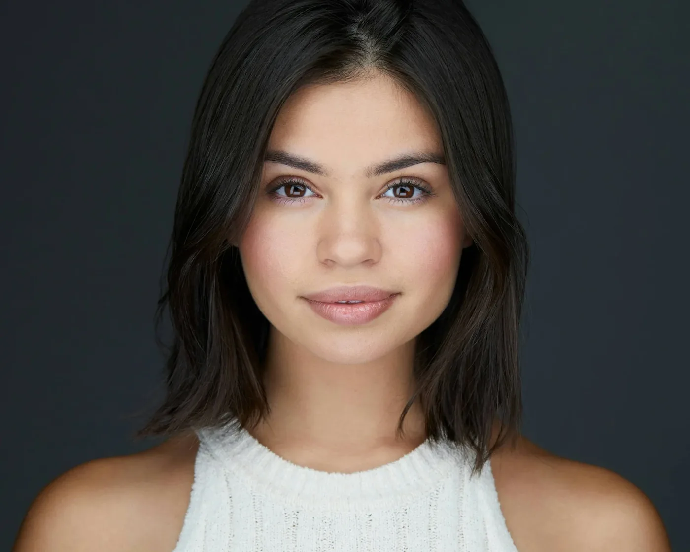 Actor headshot of a young woman with a dark bob against a charcoal backdrop
